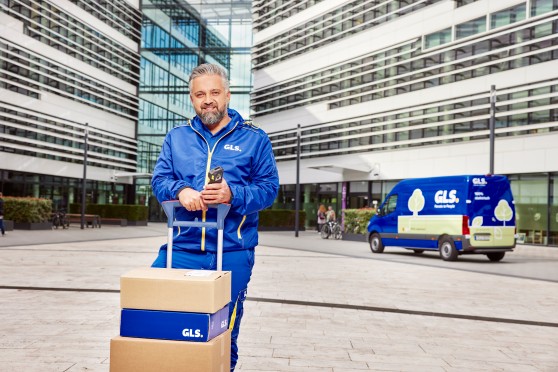 Ein GLS-Zustellfahrer mit Paketen vor seinem Zustellfahrzeug