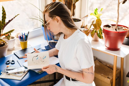 Een vrouw kijkt naar haar tekening aan haar knutseltafel