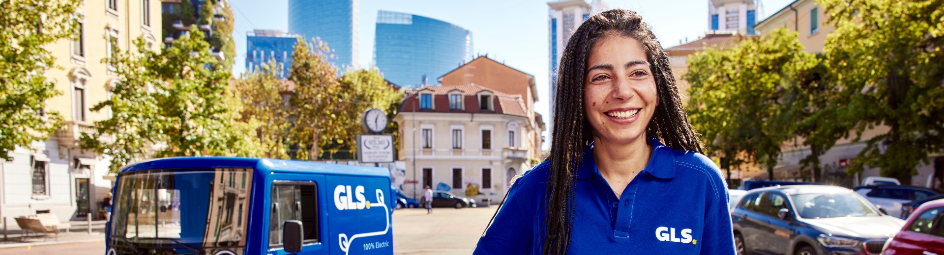 Hymyilevä GLS-työntekijä kävelee kameraa kohti