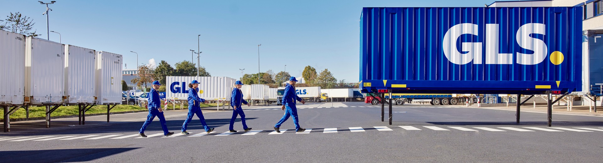 GLS:n työntekijät kävelevät peräkkäin suojatietä pitkin