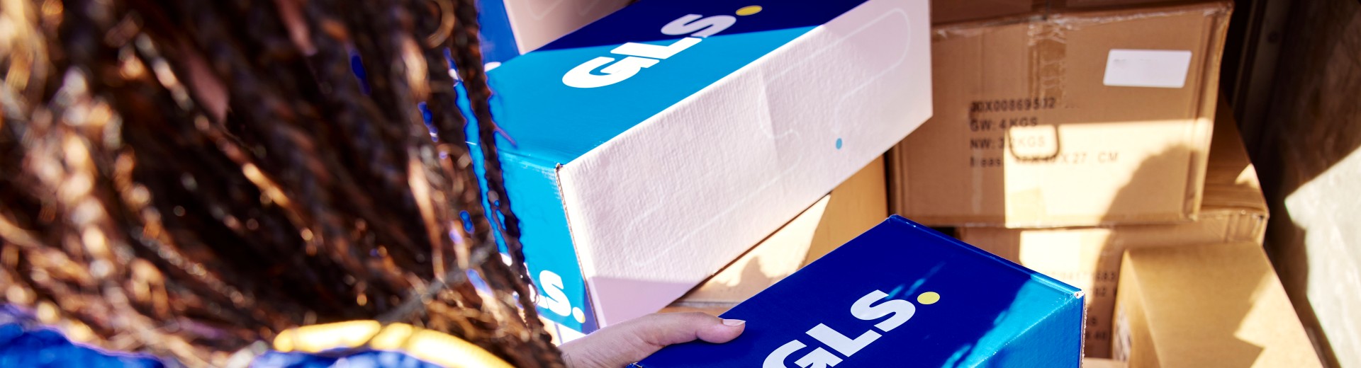 GLS-kuljettaja pitää käsissään paketteja