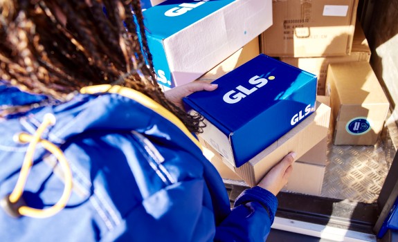 GLS-kuljettaja pitää käsissään paketteja