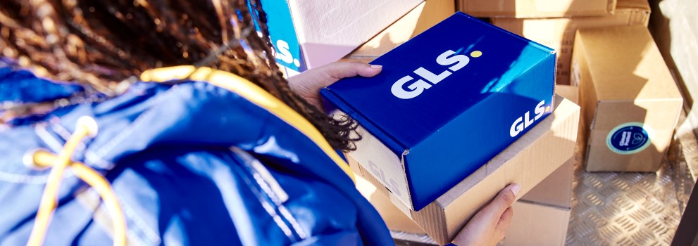 GLS-kuljettaja pitää käsissään paketteja