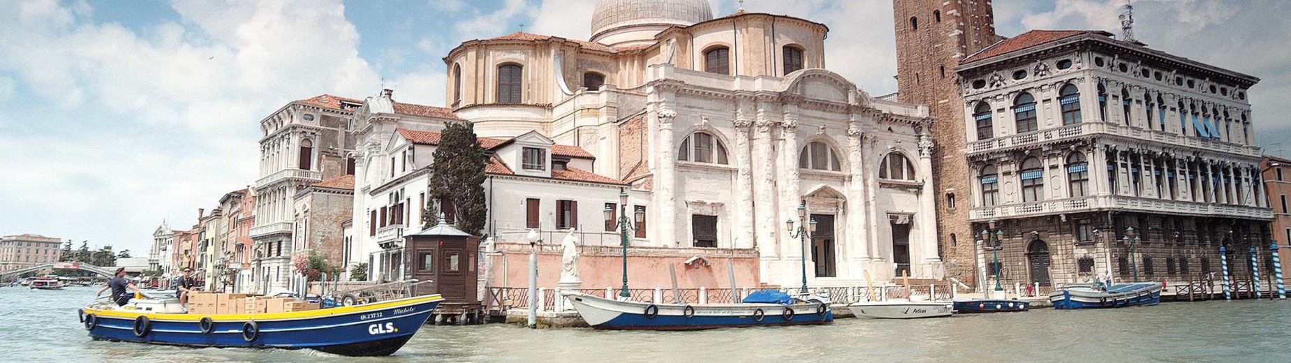 Bateau de livraison GLS transportant des colis sur un canal à Venise, illustrant le réseau européen de GLS France.