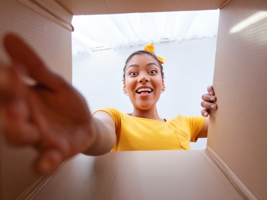 Une jeune fille déballe un colis livré par GLS France