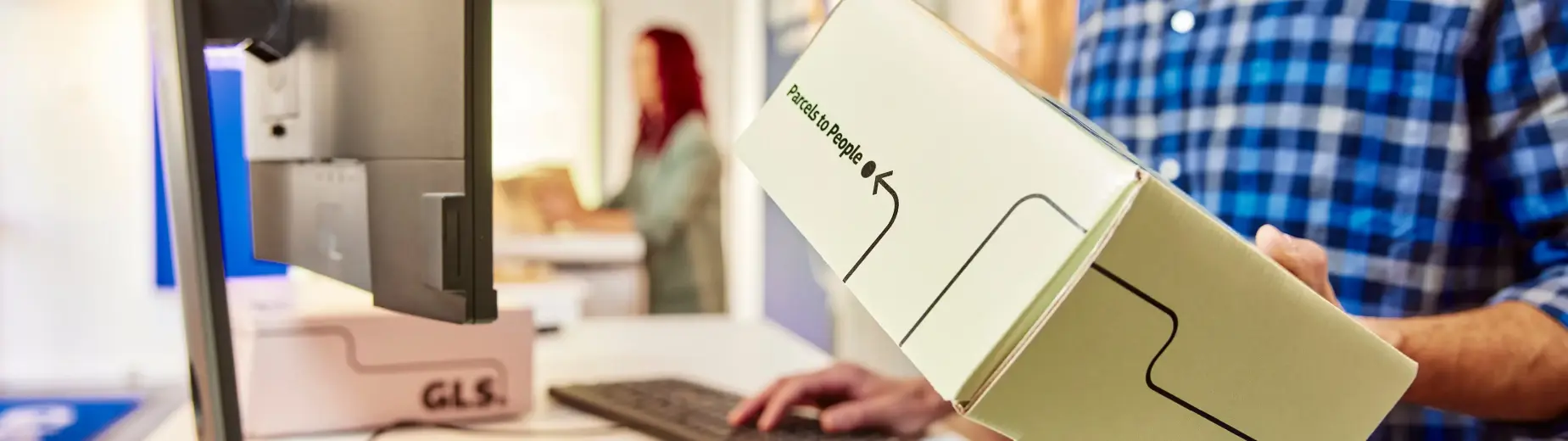 Gros plan sur un client remettant un colis GLS à un comptoir d’expédition, illustrant une solution d’envoi dédiée aux professionnels.