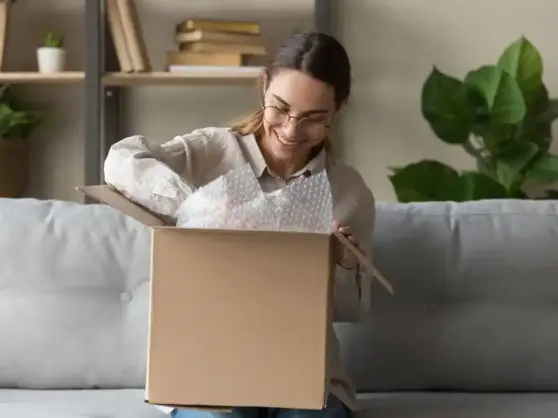 Fiatal nő kibontja a csomagját.