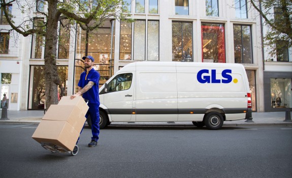 Kurir GLS raznaša pakete z vozilom GLS v ozadju
