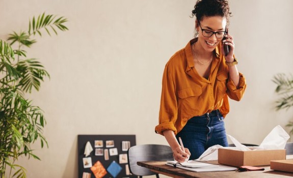 Ženska se pogovarja po telefonu in drži dokumente