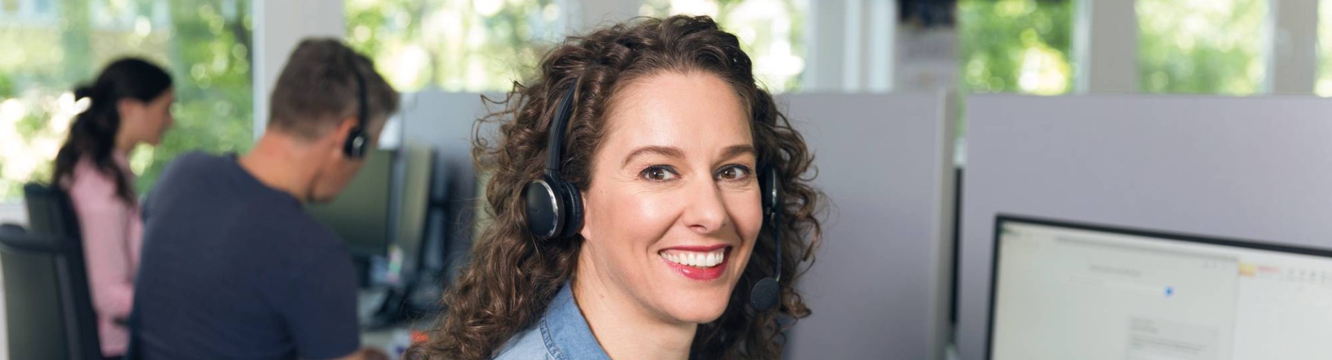 zaposlena ženska s slušalkami v kontaktnem centru pomaga strankam