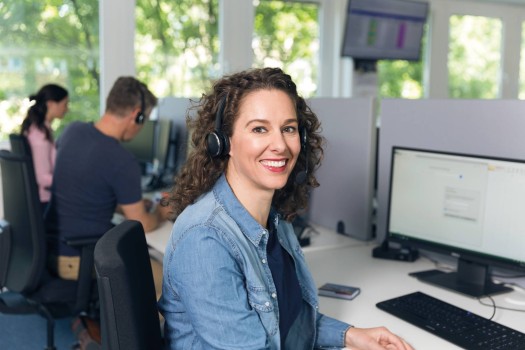 zaposlena ženska s slušalkami v kontaktnem centru pomaga strankam