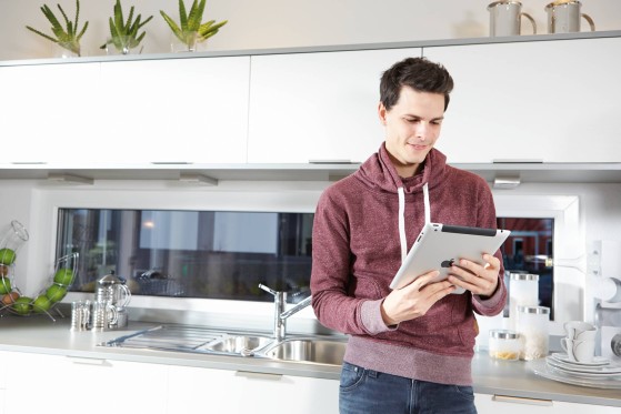 Moški stoji in gleda v zaslon tablice