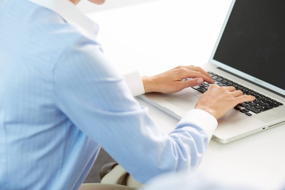 Moški v srajci tipka na prenosnik